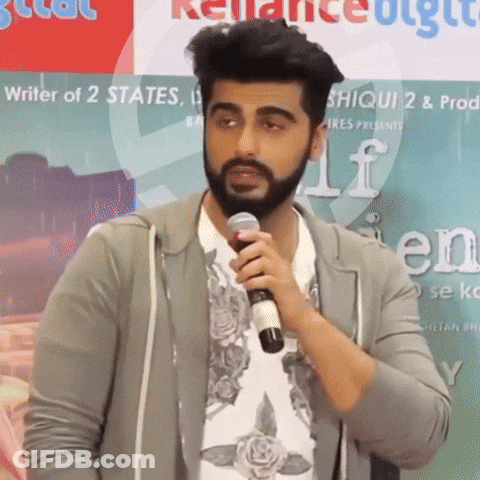 A Man With A Beard Is Holding A Microphone In Front Of A Sign That Says ' Writer Of 2 States ' GIF