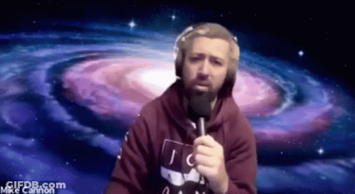 A Man With A Beard Is Holding A Microphone In Front Of A Spiral Galaxy . GIF
