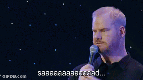 A Man With A Beard Is Holding A Microphone In Front Of Him And Saying Saaa . GIF