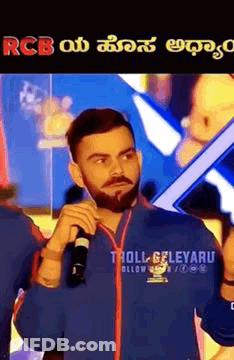 A Man With A Beard Is Holding A Microphone In His Hand And Talking Into It . GIF