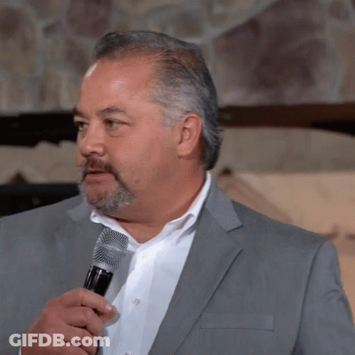A Man With A Beard Is Holding A Microphone GIF