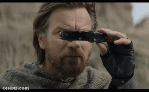 A Man With A Beard Is Holding A Pair Of Binoculars GIF