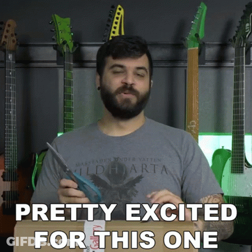A Man With A Beard Is Holding A Pair Of Scissors In Front Of A Wall Of Guitars And Says Pretty Excited GIF