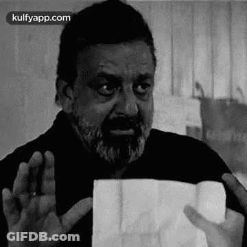 A Man With A Beard Is Holding A Piece Of Paper . GIF