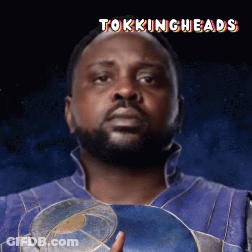 A Man With A Beard Is Holding A Shield With The Words Tokingheads Below Him GIF