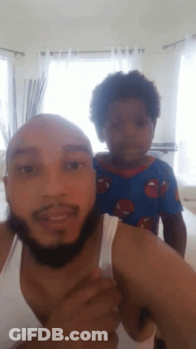 A Man With A Beard Is Holding A Small Child On His Shoulders GIF