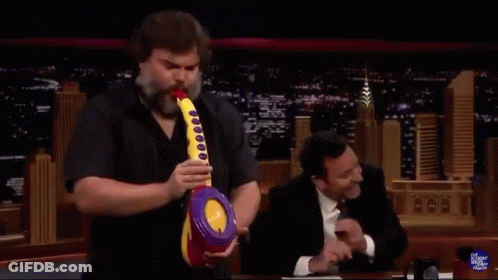 A Man With A Beard Is Holding A Toy Saxophone In Front Of Jimmy Fallon GIF