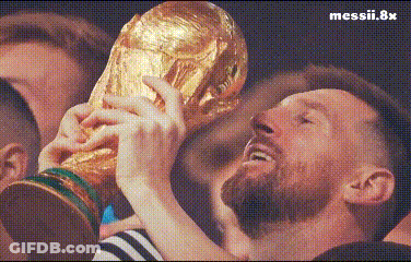 A Man With A Beard Is Holding A Trophy In His Hands In Front Of A Crowd . GIF