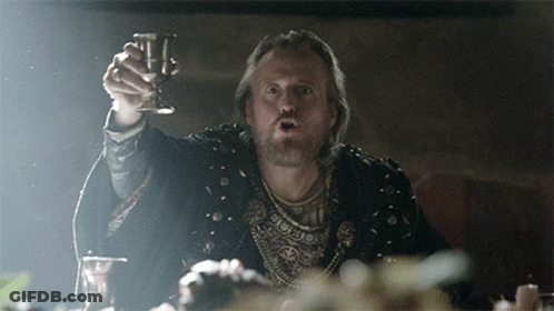 A Man With A Beard Is Holding A Wine Glass In His Hand GIF