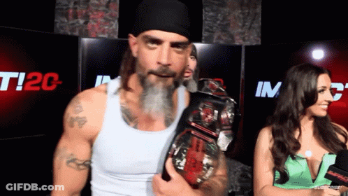 A Man With A Beard Is Holding A Wrestling Championship Belt GIF