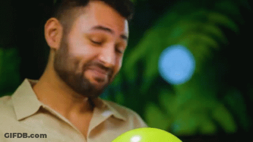 A Man With A Beard Is Holding A Yellow Ball And Making A Face . GIF