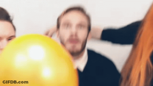 A Man With A Beard Is Holding A Yellow Balloon In Front Of His Face . GIF