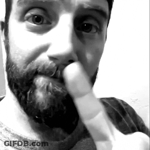 A Man With A Beard Is Holding His Finger To His Nose GIF