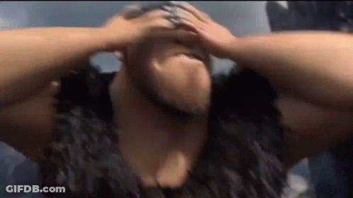 A Man With A Beard Is Holding His Head In Pain . GIF