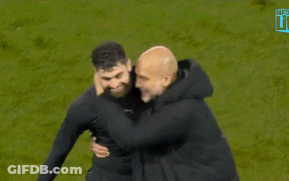 A Man With A Beard Is Hugging Another Man On A Field GIF