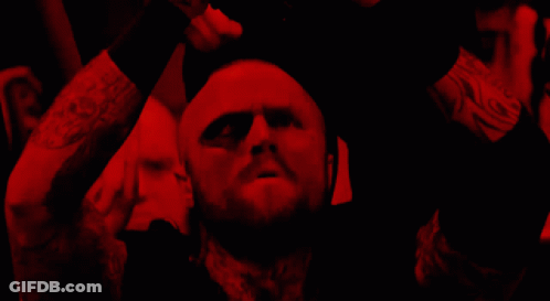 A Man With A Beard Is In A Dark Room With A Red Light Behind Him GIF