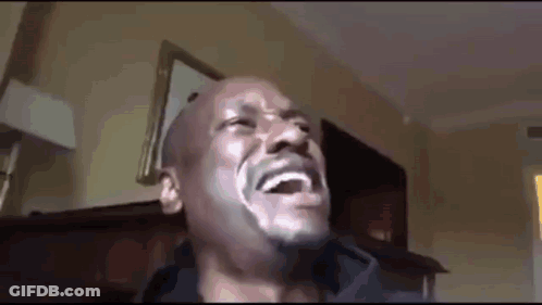 A Man With A Beard Is Laughing In A Room . GIF