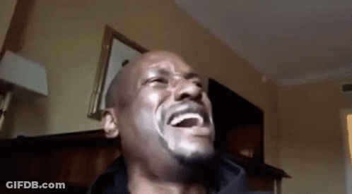 A Man With A Beard Is Laughing In A Room With His Mouth Open . GIF