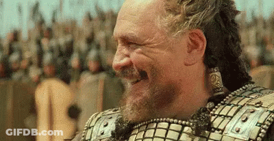 A Man With A Beard Is Laughing In Front Of A Crowd Of People In Armor . GIF