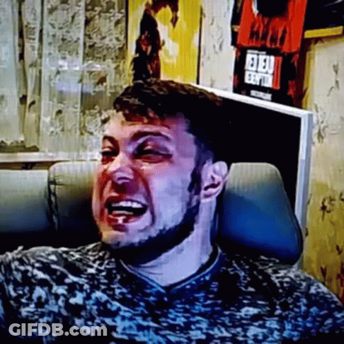 A Man With A Beard Is Laughing While Sitting In A Chair In Front Of A Television . GIF