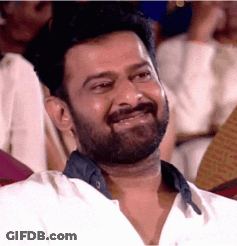 A Man With A Beard Is Laughing While Sitting In A Theatre . GIF