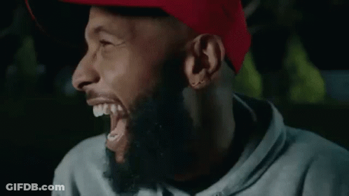 A Man With A Beard Is Laughing With His Eyes Closed And His Mouth Open . GIF