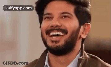 A Man With A Beard Is Laughing With His Mouth Open And His Eyes Closed . GIF