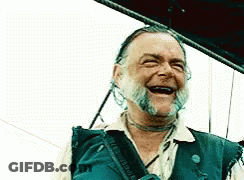 A Man With A Beard Is Laughing With His Mouth Wide Open GIF