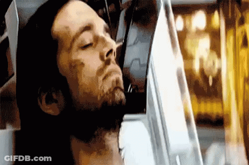 A Man With A Beard Is Laying Down In A Chair With His Eyes Closed . GIF