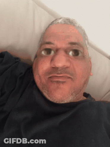 A Man With A Beard Is Laying In A Bed And Looking At The Camera GIF
