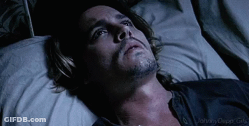 A Man With A Beard Is Laying In A Bed Looking Up At The Sky . GIF