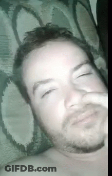 A Man With A Beard Is Laying In Bed With His Eyes Closed . GIF