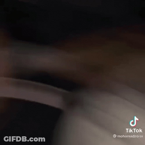 A Man With A Beard Is Laying On A Bed And Has A Tiktok On His Face . GIF