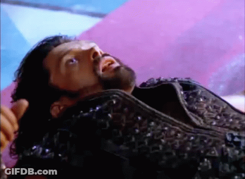 A Man With A Beard Is Laying On A Purple Blanket . GIF