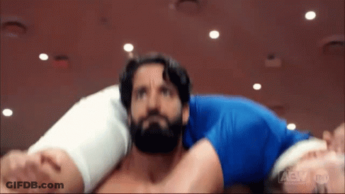 A Man With A Beard Is Laying On Another Man 'S Shoulders In A Wrestling Ring . GIF