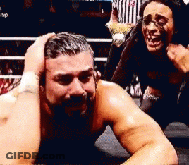 A Man With A Beard Is Laying On The Ground In A Boxing Ring While A Woman Holds His Head . GIF