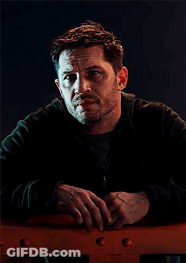 A Man With A Beard Is Leaning Against A Railing And Looking At The Camera GIF