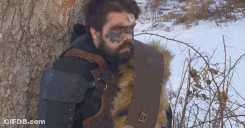 A Man With A Beard Is Leaning Against A Tree GIF