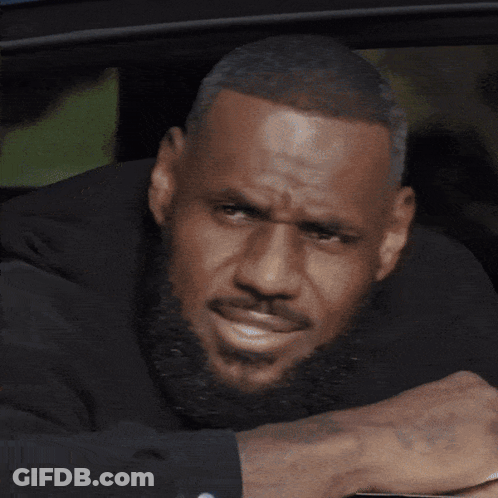 A Man With A Beard Is Leaning On A Table With His Head Resting On His Hand GIF