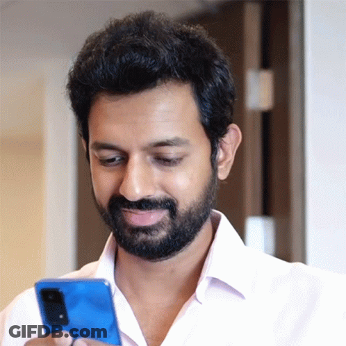 A Man With A Beard Is Looking At A Blue Cell Phone GIF