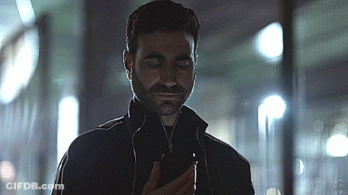 A Man With A Beard Is Looking At A Cell Phone GIF