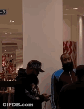 A Man With A Beard Is Looking At His Phone While Standing In A Store GIF