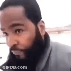 A Man With A Beard Is Looking At The Camera In A Close Up . GIF