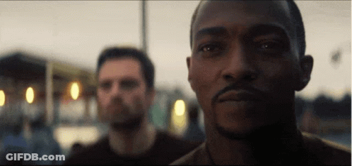 A Man With A Beard Is Looking At The Camera While Another Man Looks On . GIF