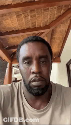 A Man With A Beard Is Looking At The Camera With A Wooden Ceiling In The Background GIF
