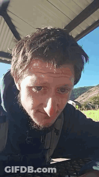 A Man With A Beard Is Looking At The Camera With His Eyes Closed GIF