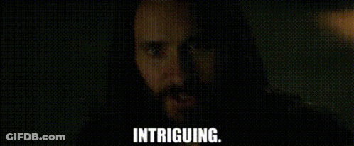 A Man With A Beard Is Looking At The Camera With The Words Intriguing . GIF