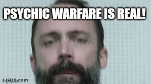 A Man With A Beard Is Looking At The Camera With The Words `` Psychic Warfare Is Real '' Written Below Him . GIF