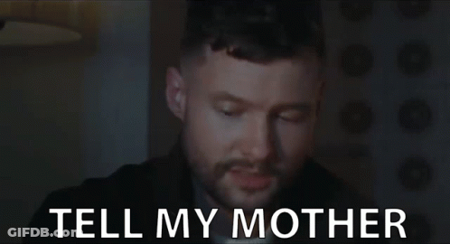 A Man With A Beard Is Looking At The Camera With The Words Tell My Mother Behind Him . GIF