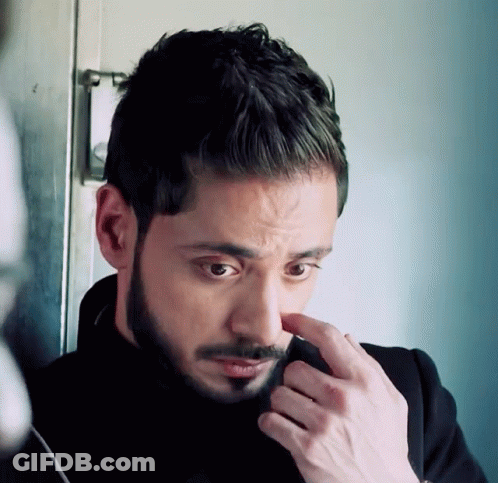 A Man With A Beard Is Looking Down At Something GIF